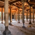Intricately carved wooden pillars inside the historic Djuma Mosque in the ancient city of Khiva, Uzbekistan.