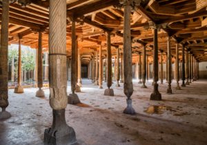 Intricately carved wooden pillars inside the historic Djuma Mosque in the ancient city of Khiva, Uzbekistan.