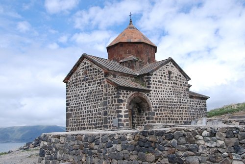 Ancient Armenian monastery perched on a red sandstone cliff in the Caucasus mountains during a guided small-group tour.