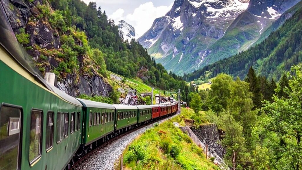 The Flåm Railway train traveling through steep mountains and waterfalls in western Norway.