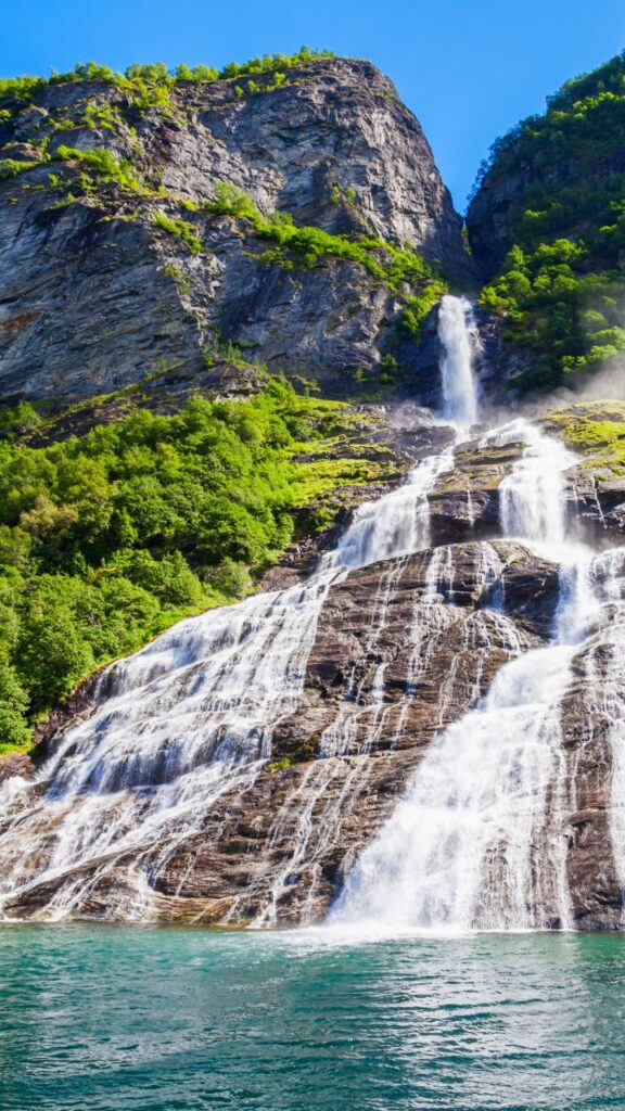 A powerful waterfall cascading down steep cliffs into Geirangerfjord in western Norway.