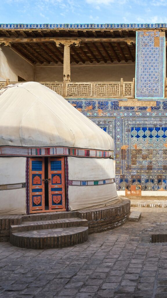 A traditional Central Asian yurt with colorful textiles set against a scenic backdrop on an Uzbekistan tour.