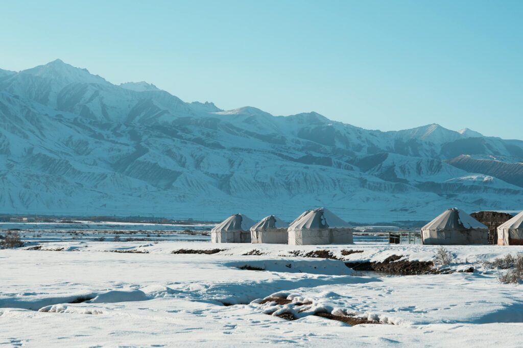 Traditional nomadic yurts nestled in a snowy valley of the majestic Pamir Mountains in Tajikistan.