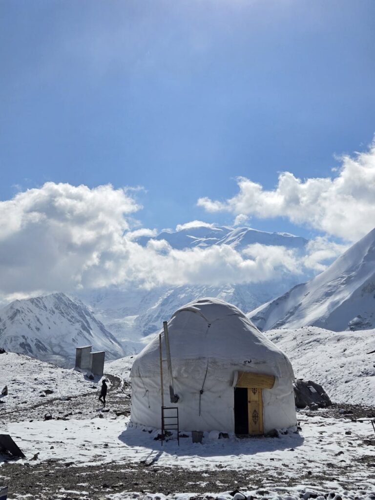 High-altitude nomadic yurt settlement nestled in the rugged, snow-capped Pamir Mountains of Tajikistan.