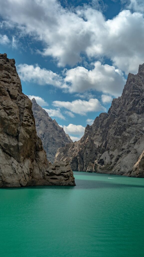 Pristine turquoise alpine lake nestled between dramatic rocky cliffs in the Pamir Mountains of Tajikistan.