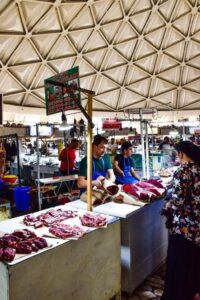 Vibrant scene at Chorsu Bazaar in Tashkent with vendors selling fresh meat