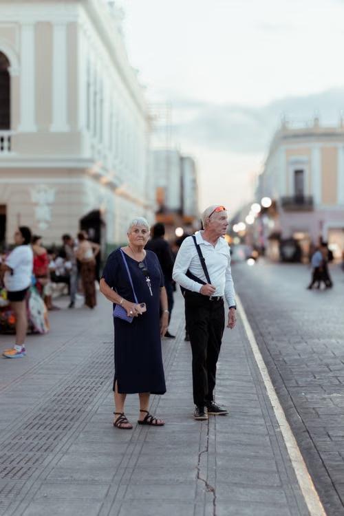 Senior couple standing on a bustling urban sidewalk during daytime travel