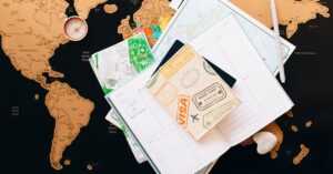 A flat lay of travel planning items including a passport, compass, and notebook