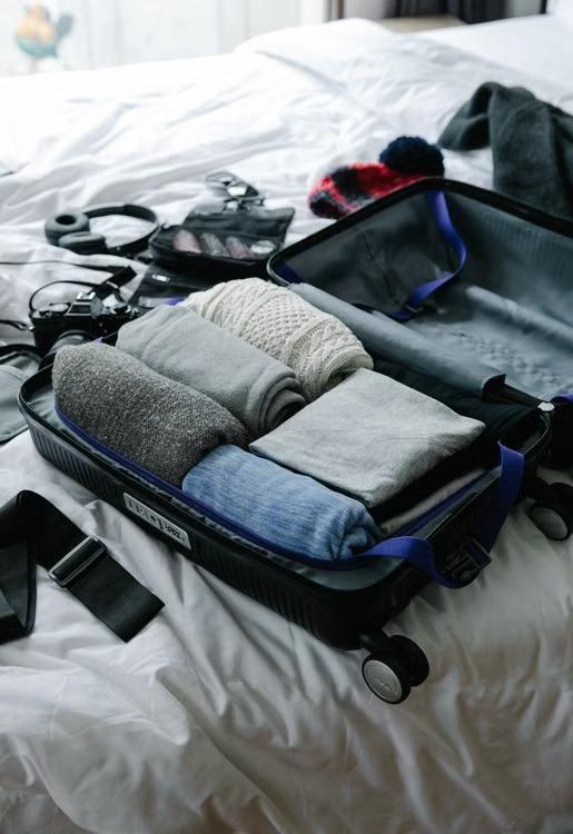 Open suitcase filled with neatly folded clothes on a bed, ready for travel