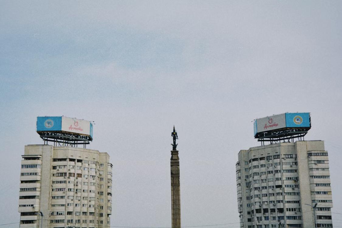 Soviet-style buildings and a monument in Almaty, Kazakhstan under a clear sky