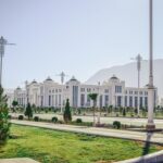 White marble building with landscaped grounds and mountain scenery in Ashgabat, Turkmenistan.