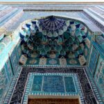 Intricate blue and turquoise tilework surrounding an ornate arched entrance in Samarkand, Uzbekistan.
