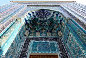 Intricate blue and turquoise tilework surrounding an ornate arched entrance in Samarkand, Uzbekistan.