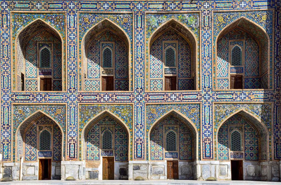 Row of pointed arches covered in intricate blue, turquoise, and gold tilework in Samarkand, Uzbekistan.