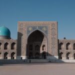 Ornate Islamic architecture with turquoise domes and a large tiled entrance at Registan Square in Samarkand, Uzbekistan.