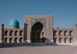 Ornate Islamic architecture with turquoise domes and a large tiled entrance at Registan Square in Samarkand, Uzbekistan.