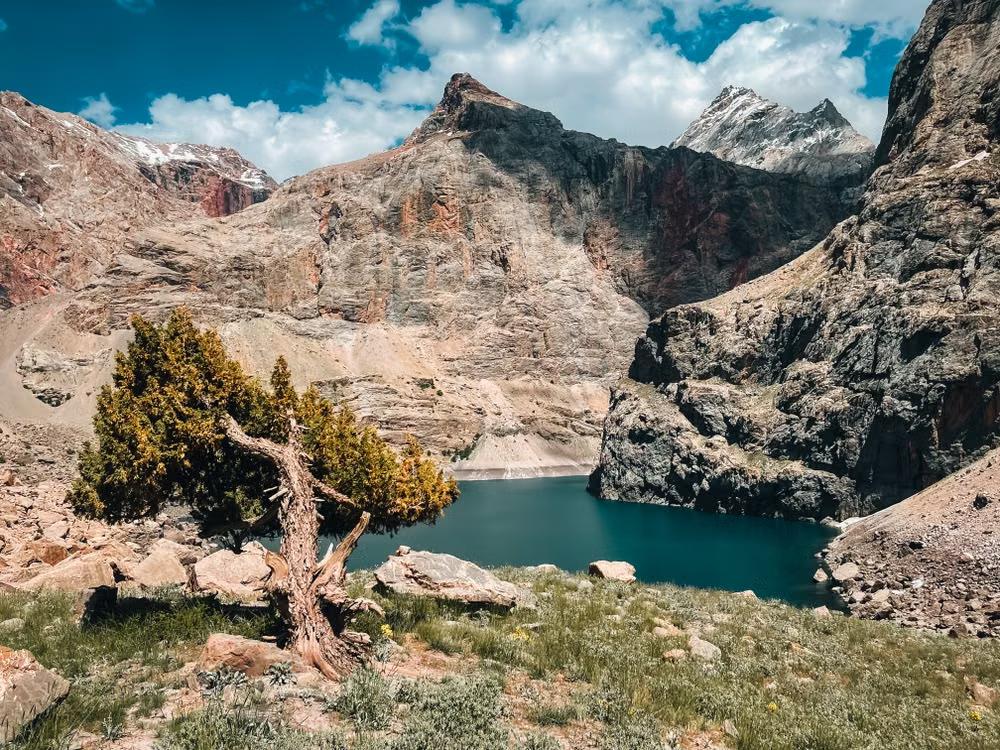 Turquoise alpine lake surrounded by rugged mountains and snow-capped peaks in Tajikistan.